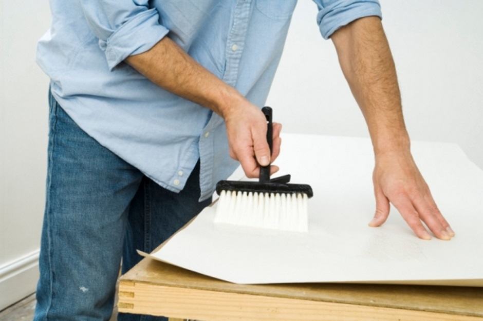 Application de colle sur la base du papier peint photo. En plus d'une brosse large, pour plus de commodité, vous pouvez utiliser le rouleau, ce qui accélérera considérablement le processus