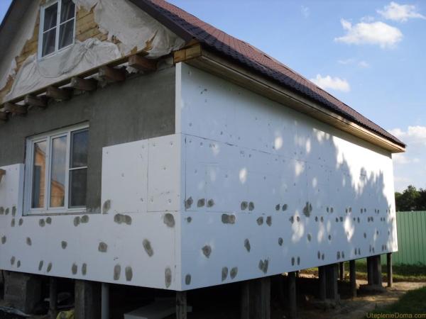 Maison en bois isolée avec des panneaux de mousse. Le mortier de ciment couvre les capuchons des chevilles en plastique qui retiennent le matériau Maison en bois isolée avec des panneaux de mousse. Le mortier de ciment couvre les capuchons des chevilles en plastique qui retiennent le matériau