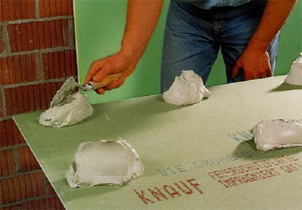 Application de colle sur les cloisons sèches pour le revêtement d'un mur de briques Application de colle sur les cloisons sèches pour le revêtement d'un mur de briques