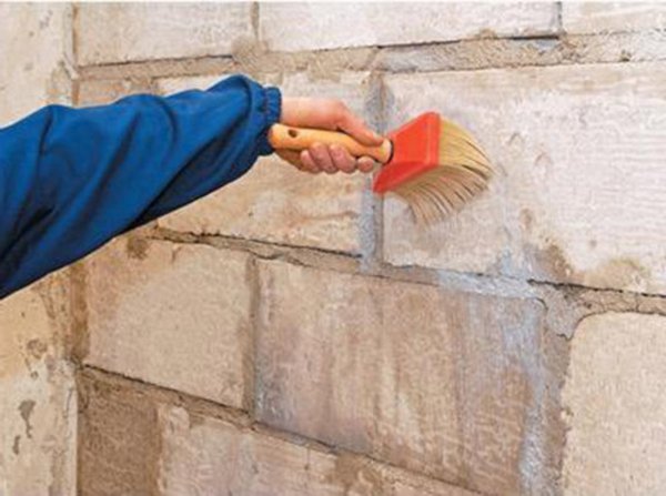 La photo montre le processus de préparation des murs de briques avec une composition spéciale, avant de les coller avec des plaques de plâtre La photo montre le processus de préparation des murs de briques avec une composition spéciale, avant de les coller avec des plaques de plâtre