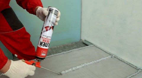 Nous voyons le processus d'application de colle sur une feuille de mousse, pour son installation ultérieure sur le mur Nous voyons le processus d'application de colle sur une feuille de mousse, pour son installation ultérieure sur le mur